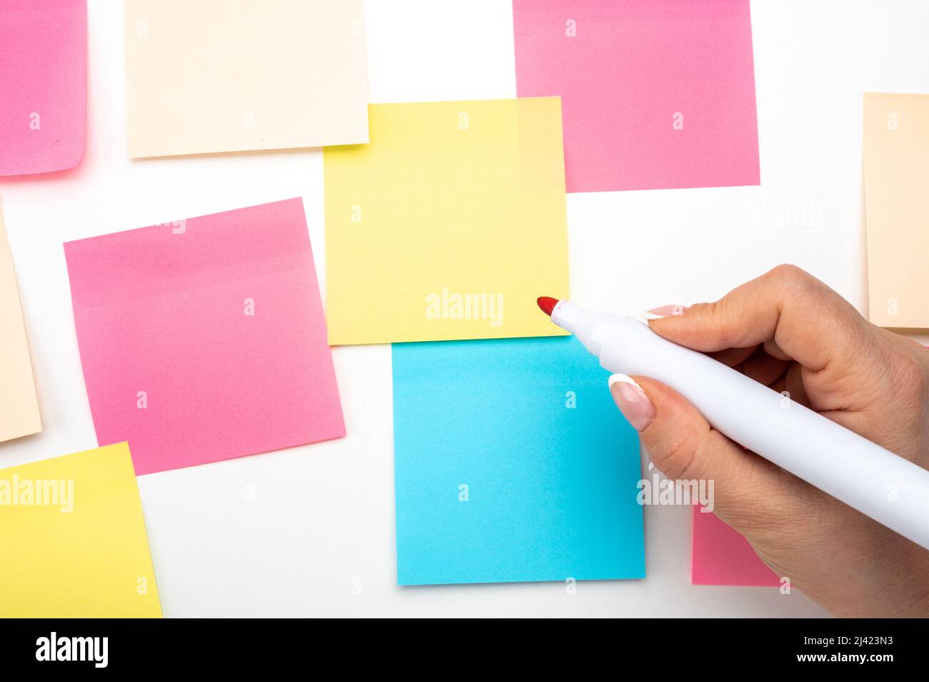 Hand schriftliche Notizen roten Marker Aufkleber Notizen Papier. Hand mit roten Marker bereit zu schreiben. Viele farbige leere Aufkleber an der Wand. Geschäftsleute treffen sich Stockfoto