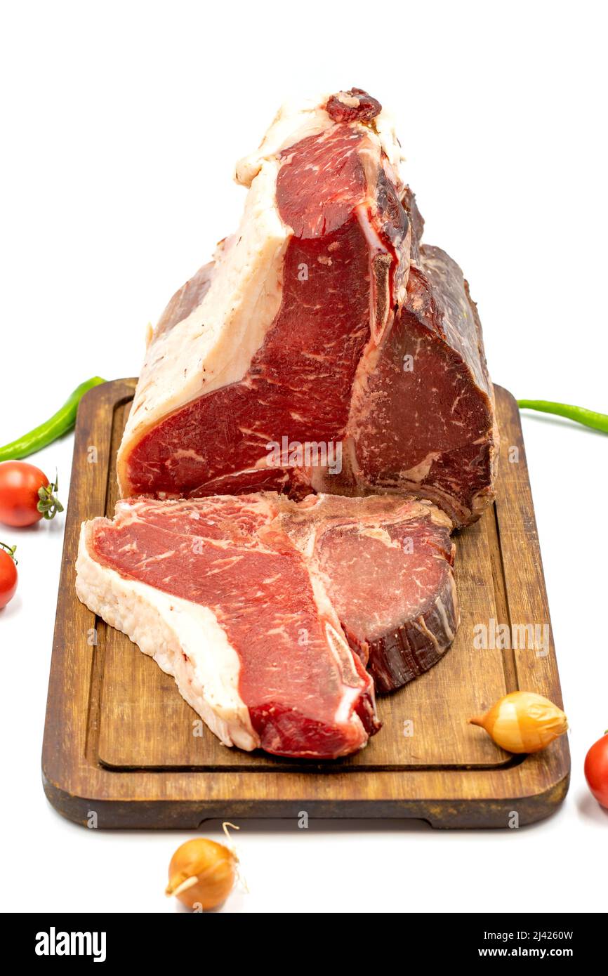 Trocken gereiftes Roh-T-Bone- oder Porterhouse-Rindfleisch-Steak mit Tomaten und Paprika. Weißer Hintergrund. Yakın çekim Stockfoto