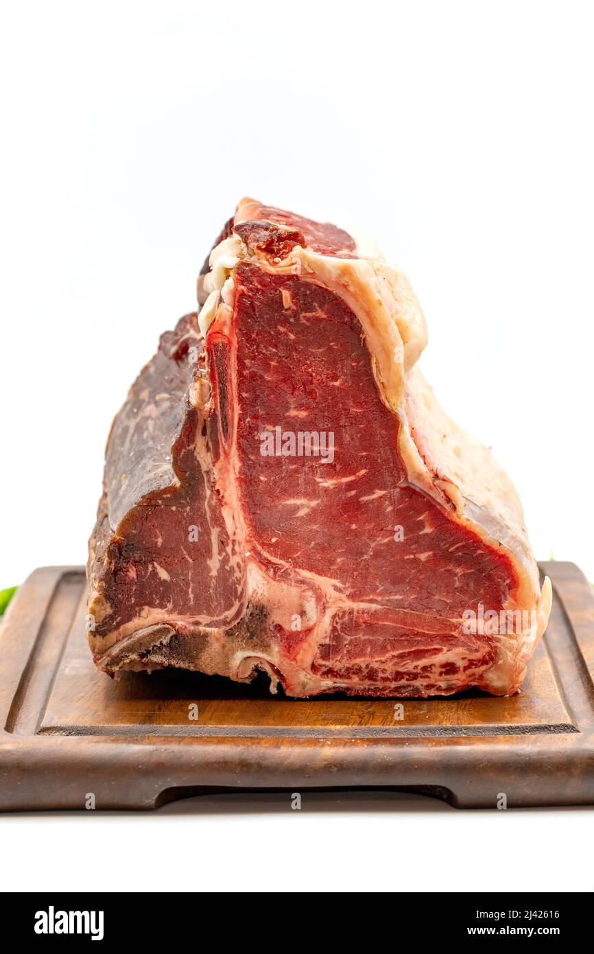 Trocken gereiftes Roh-T-Bone- oder Porterhouse-Rindfleisch-Steak mit Tomaten und Paprika. Weißer Hintergrund. Yakın çekim Stockfoto