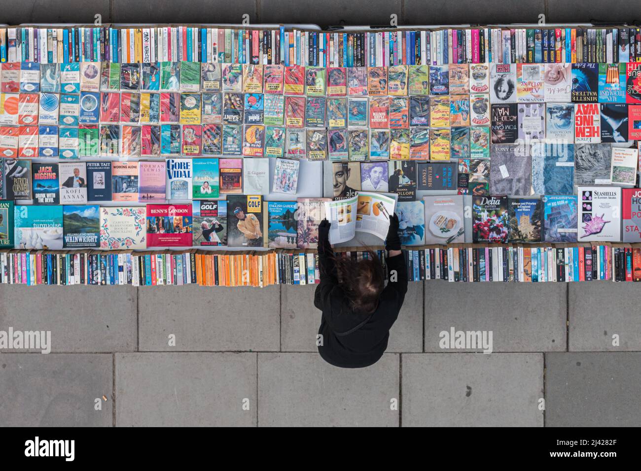 London, Vereinigtes Königreich - 22. Oktober 2016: Alleinerziehende Frau blättert durch Seiten eines Gebrauchtbuches im Buchmarktstand auf der Southbank in London Stockfoto