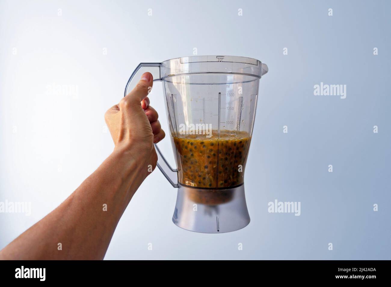 Mixbecher mit Passionsfrucht-Fruchtfleisch auf der Hand Stockfoto
