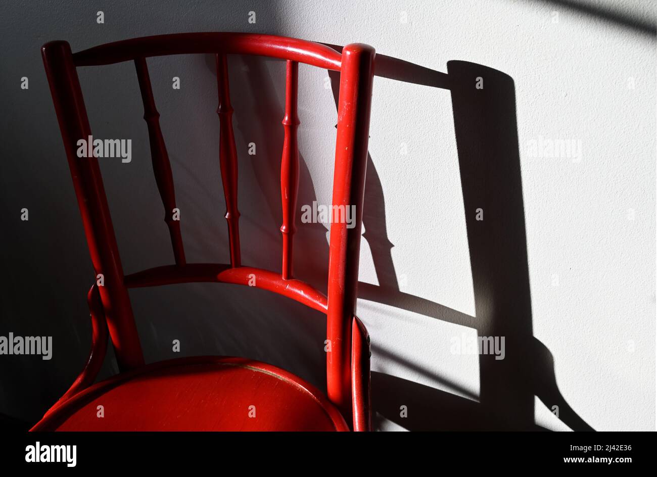 Roter Vintage-Stuhl und sein Schatten an der Wand Stockfoto