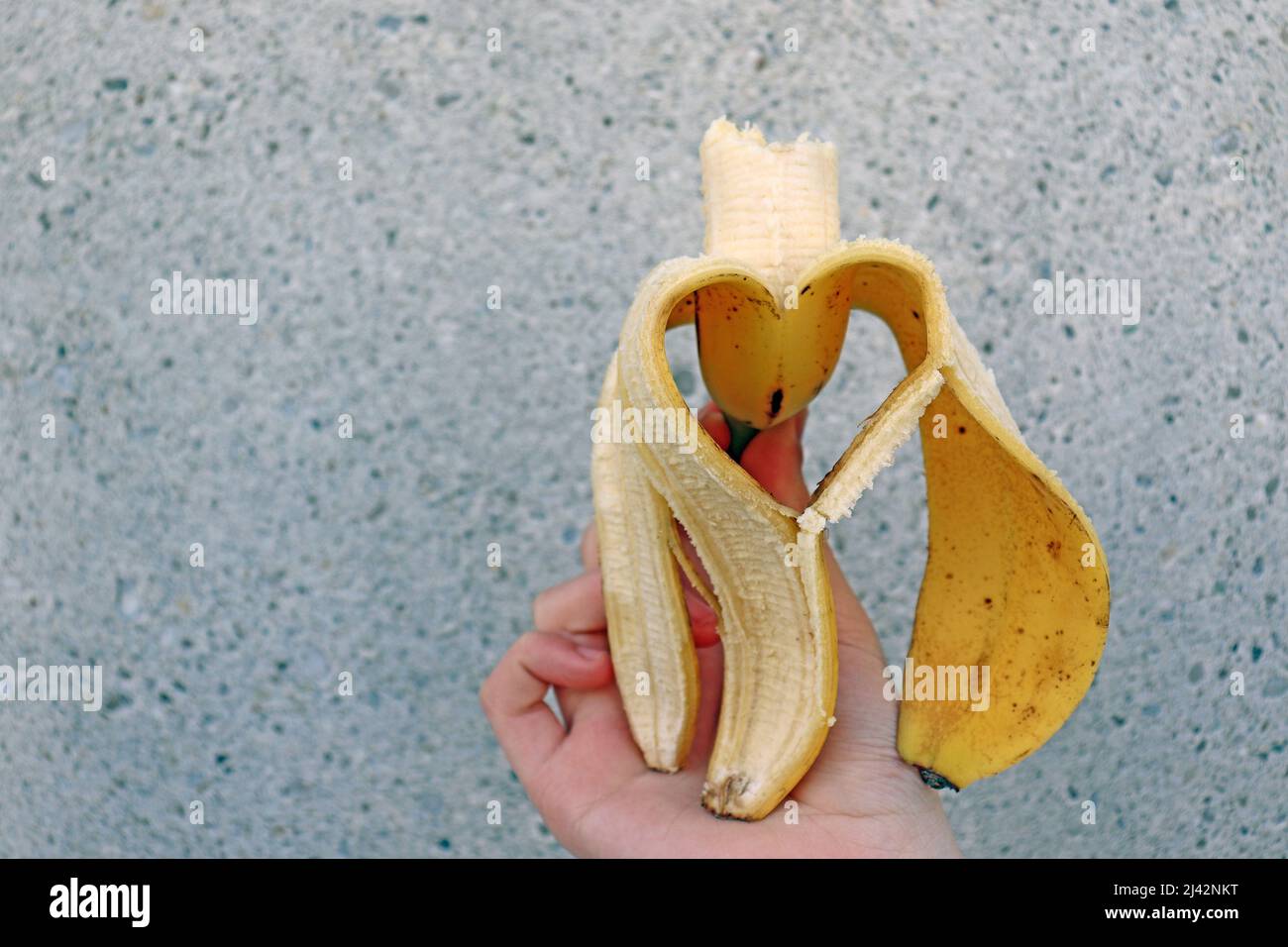 Geschälte Banane in Form eines Herzens, die die Liebe zur Eat Banane darstellt. Gesunde Ernährung, essen Banane. Herzförmige geschälte Banane Stockfoto