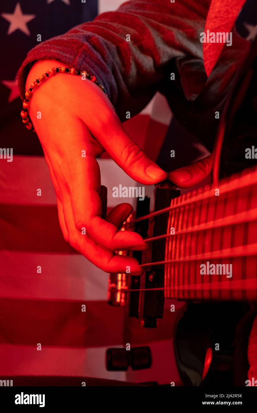 Hände spielen eine E-Gitarre mit einem roten Licht Stockfoto
