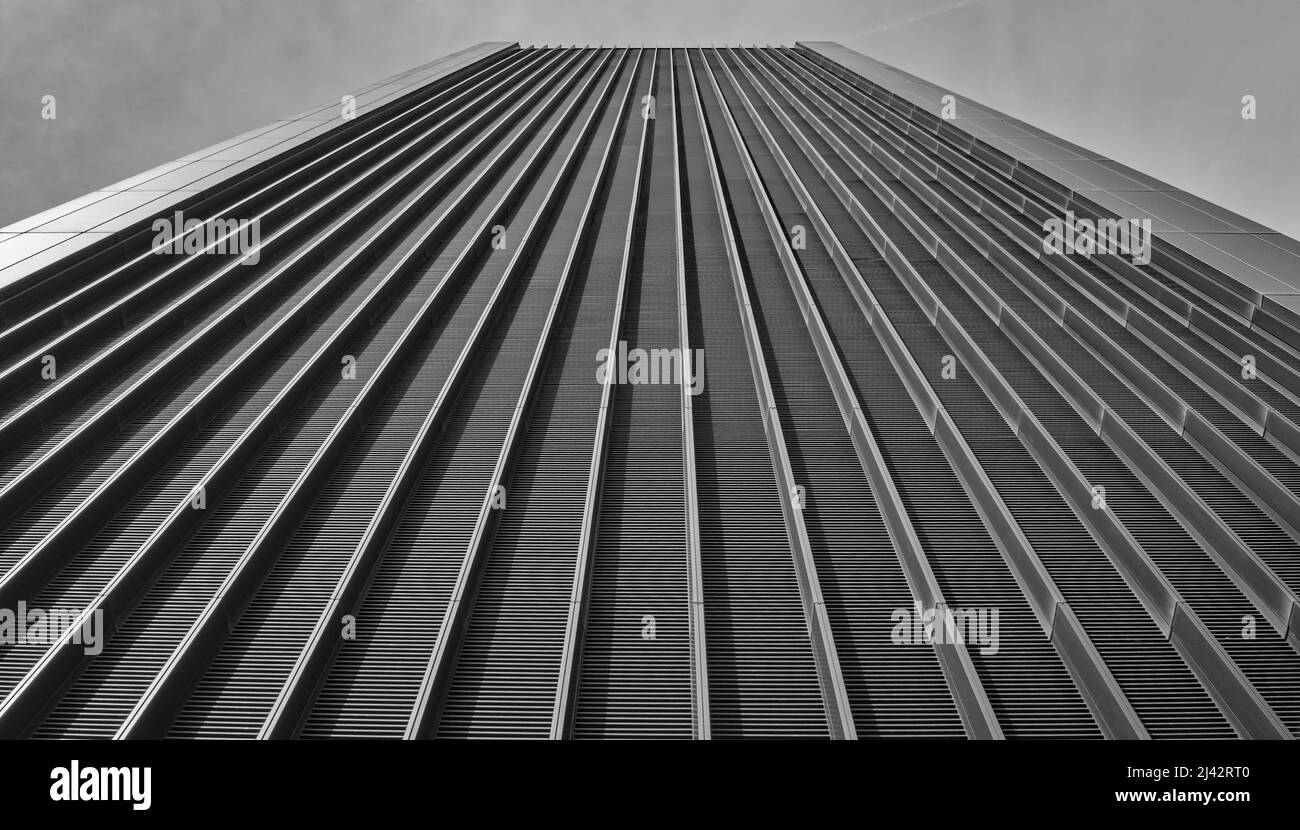 Ein schwarz-weißes Bild eines hohen futuristischen londoner Gebäudes mit Schienen, die nach oben führen Stockfoto