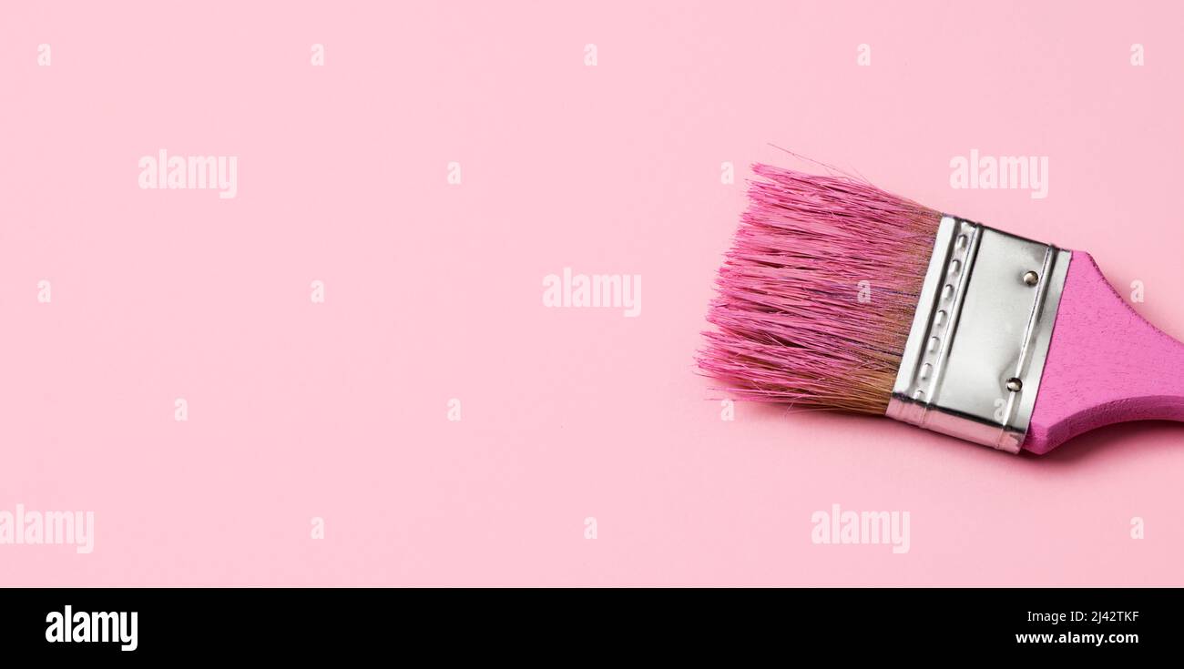 Nahaufnahme eines rosa Pinsels mit etwas rosa Farbe, auf einem hellrosa Hintergrund mit etwas leerem Raum auf der linken Seite, in einem Panorama-Format als Web BA zu verwenden Stockfoto