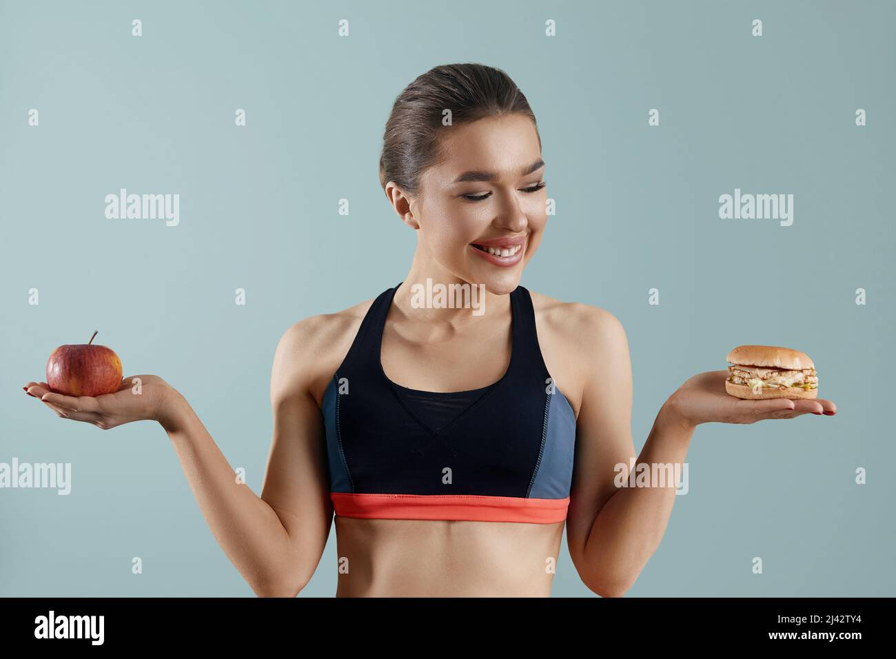 Frau, die zwischen Apfel und Hamburger wählen kann. Diät-Konzept. Gesunde Ernährung, Stockfoto