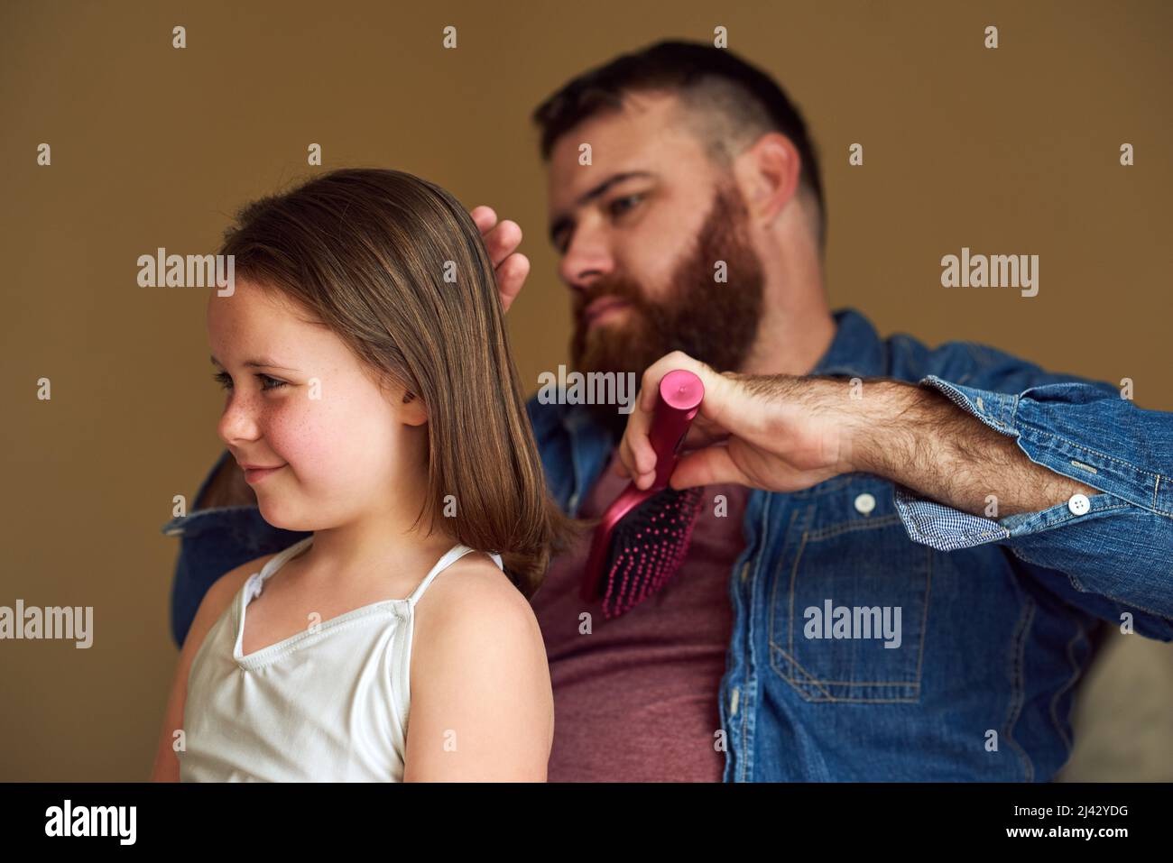 Inspirierende Momente. Aufnahme eines Vaters, der sich zu Hause die Haare seiner Tochter putzt. Stockfoto