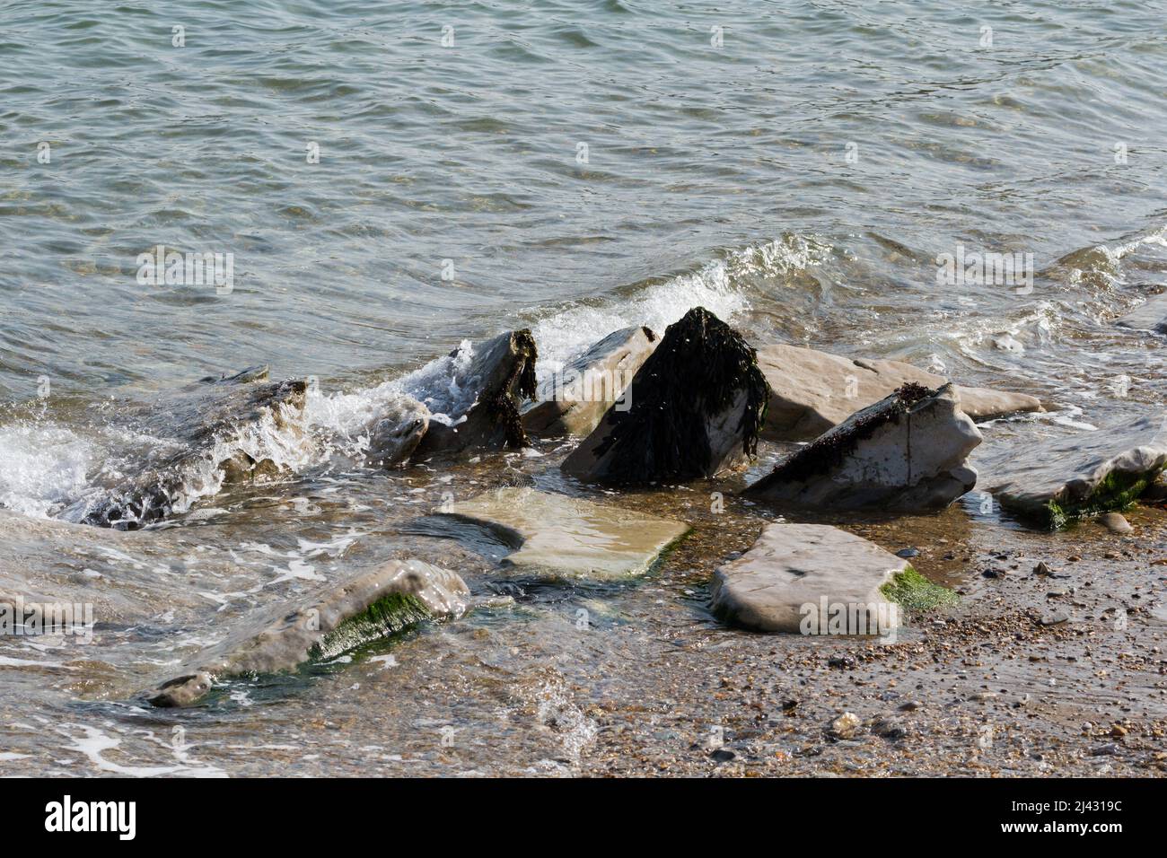 Meereswellen brechen sanft über Felsen am Strand von Swanage, Dorset, England Stockfoto