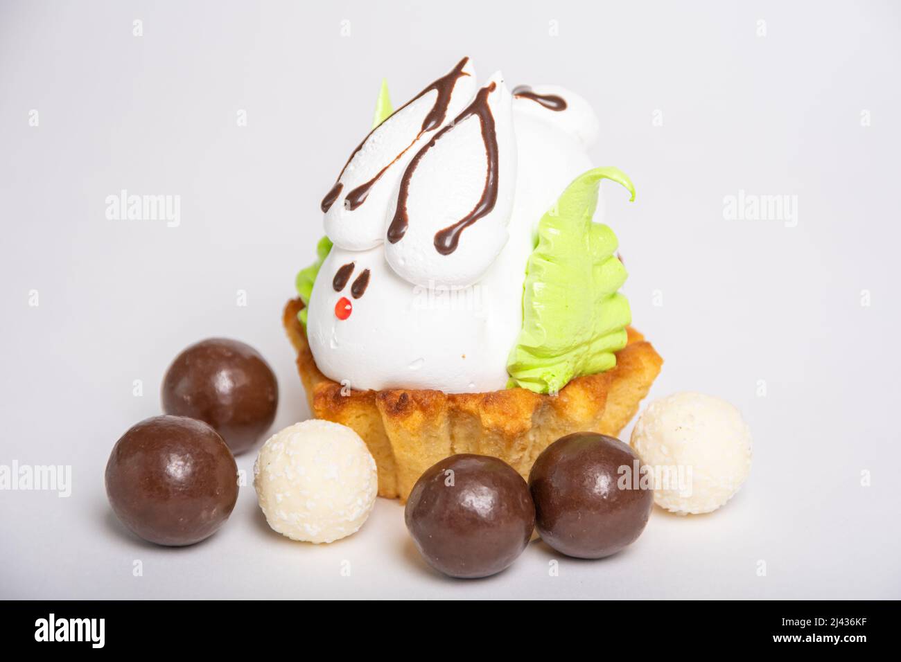 Seitenansicht eines hausgemachten Proteinkuchens in Form eines Osterhasen, der auf einem Keks inmitten von runden Pralinen eingebettet ist. Süße Ostertradition. Sprotte Stockfoto