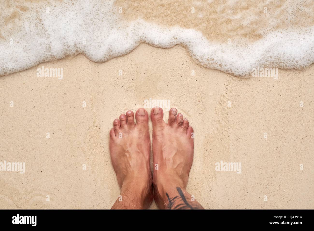 Salziges Haar und sandige Zehen. High-Angle-Aufnahme von den Füßen eines mannes am Strand. Stockfoto