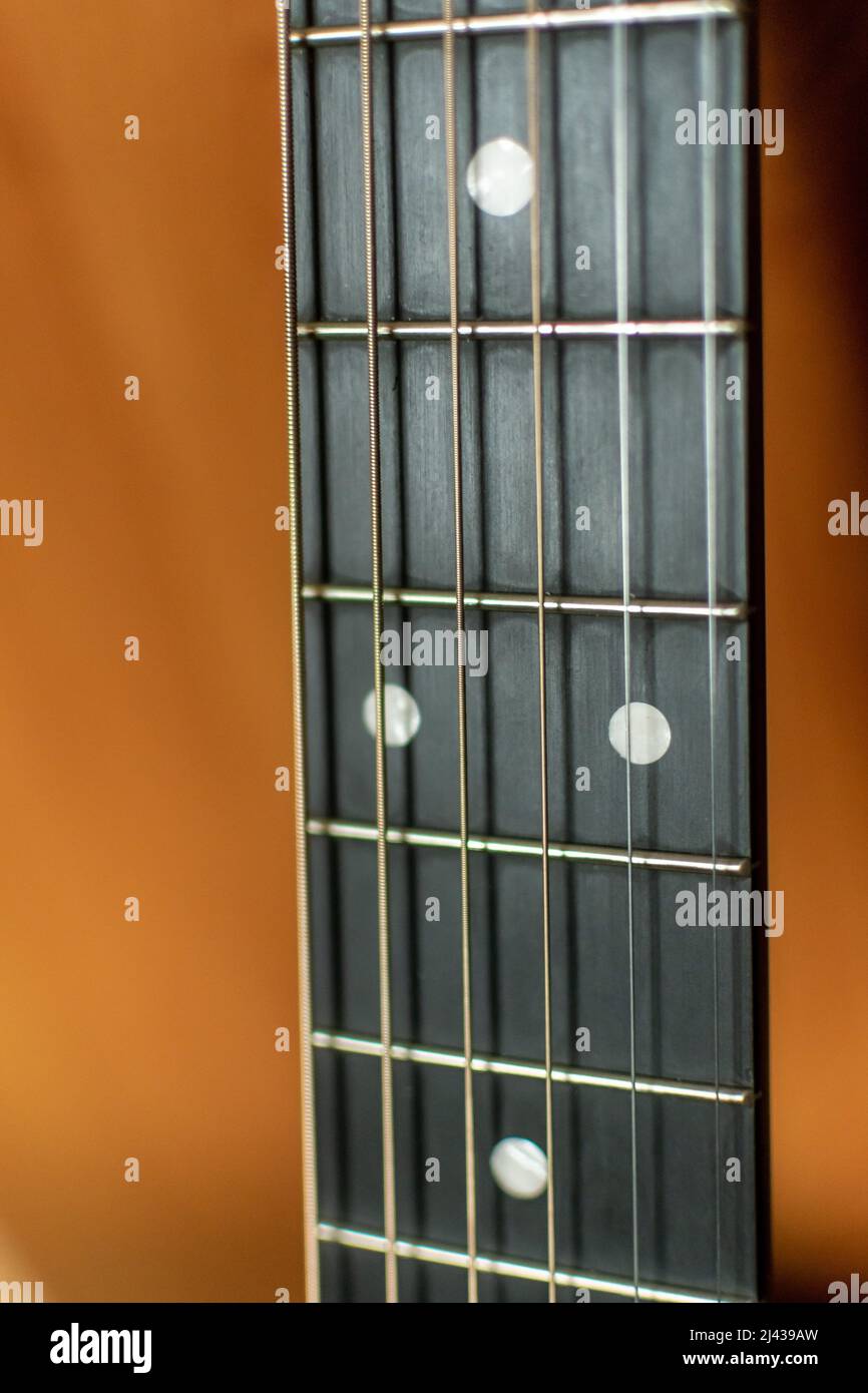 Eine Nahaufnahme des Halses einer akustischen Gitarre mit Positionsmarkierungen, Bünde und Griffbrett und Stahlsaiten Stockfoto