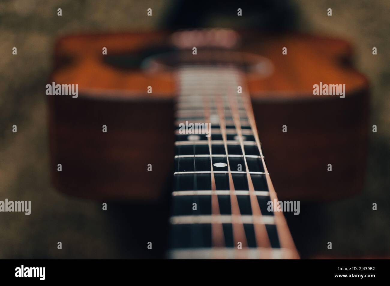 Blick auf den Hals einer akustischen Gitarre konzentriert sich auf das Griffbrett, Bund und Position Marker mit einem verschwommenen Hintergrund Stockfoto