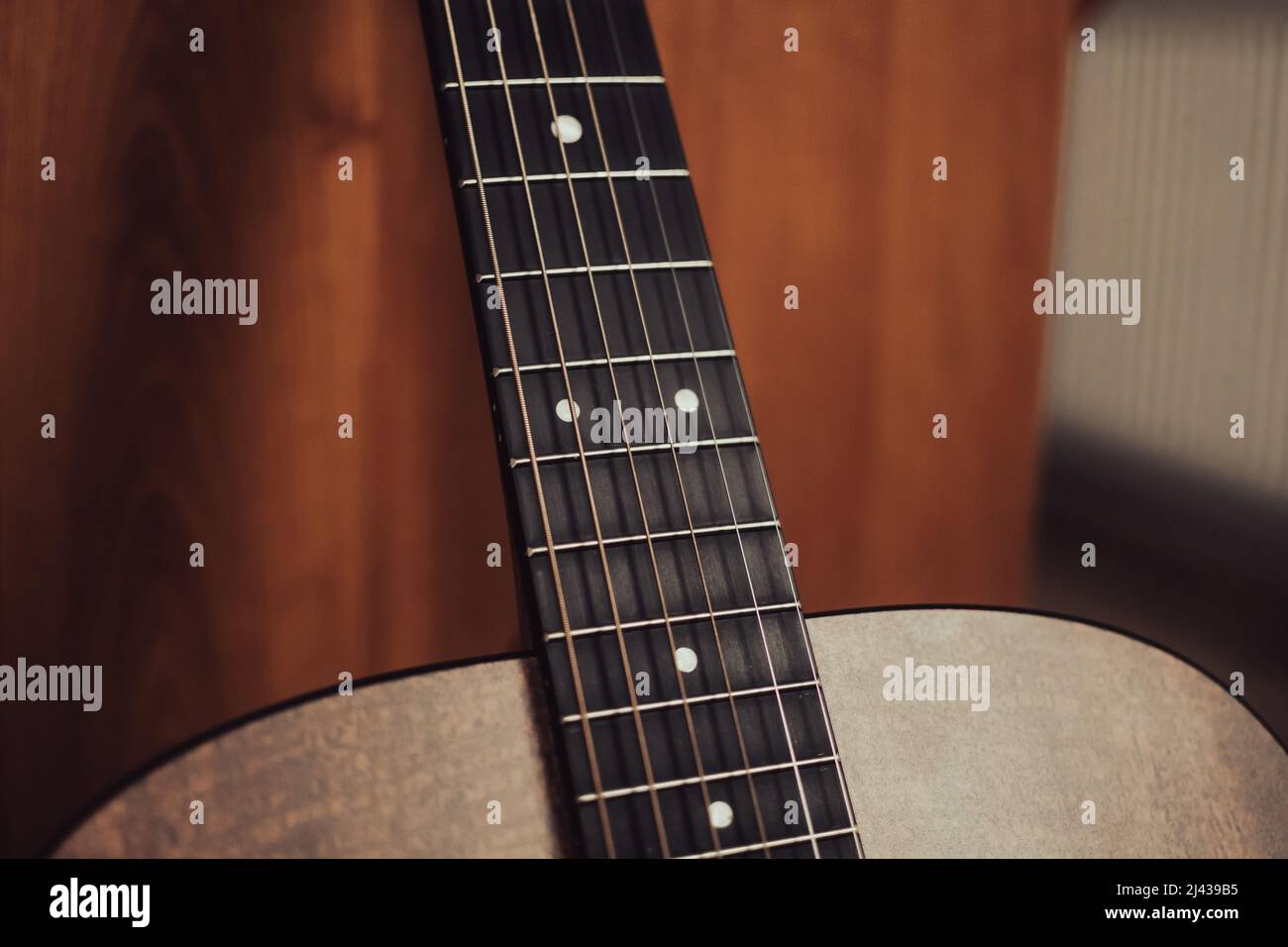 Eine abgewinkelte Ansicht des Halses einer akustischen Gitarre mit Griffbrett, Bünde, Positionsmarkierungen und Saiten. Stockfoto
