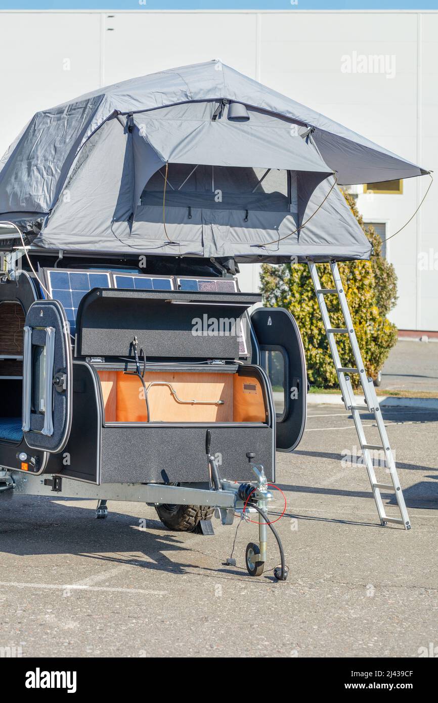 Wohnwagenhaus mit Solarpanel und einem klappbaren Zelt mit Schlafplätzen auf dem Dach. Stockfoto