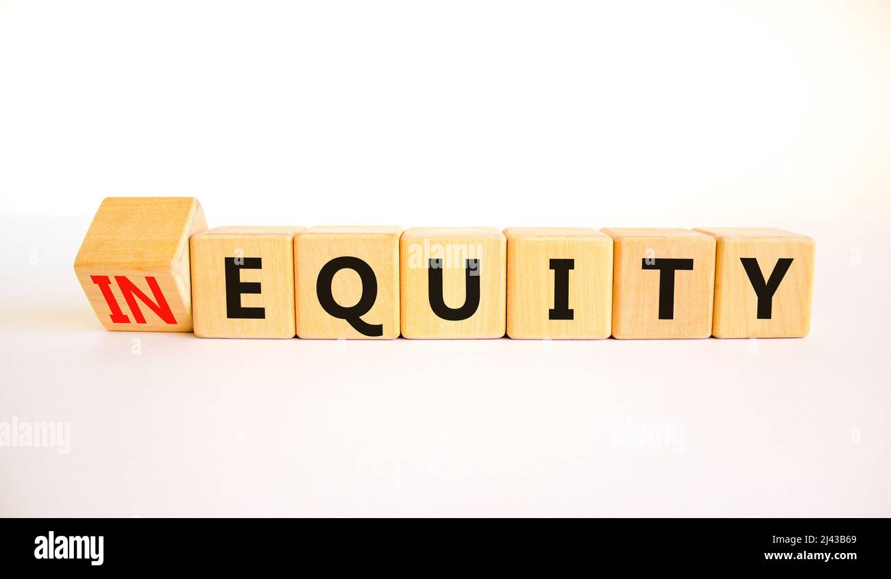 Symbol für Ungleichheit oder Eigenkapital. Drehten Holzwürfel und änderten das Konzeptwort InEquity in Equity. Schöne weiße Tabelle weißen Hintergrund. Business und ich Stockfoto
