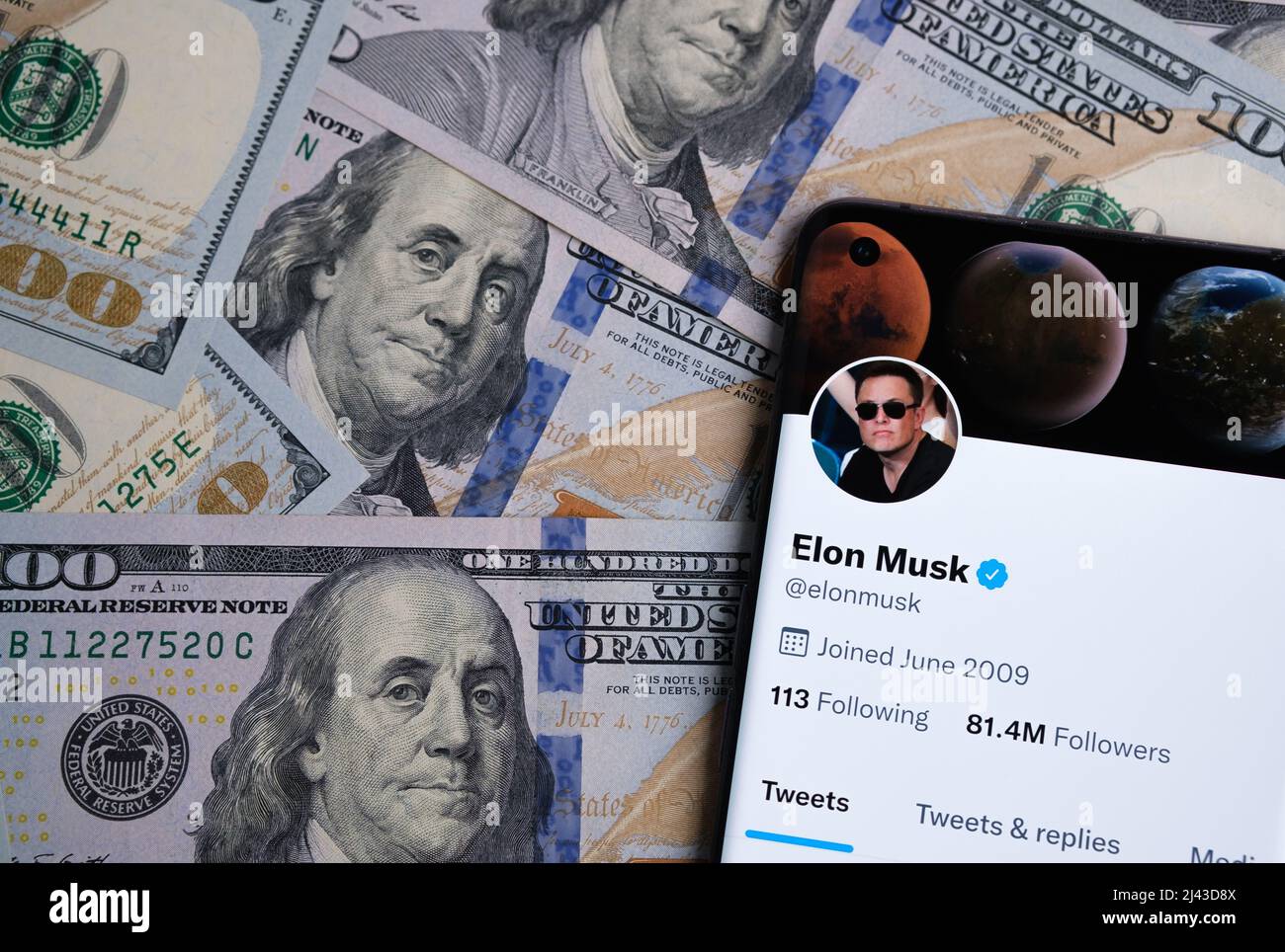 Offizielle Twitter-Account-Seite von Elon Musk auf dem Smartphone, das auf dem Stapel von Dollar-Banknoten platziert ist. Konzept. Stafford, Großbritannien, A Stockfoto