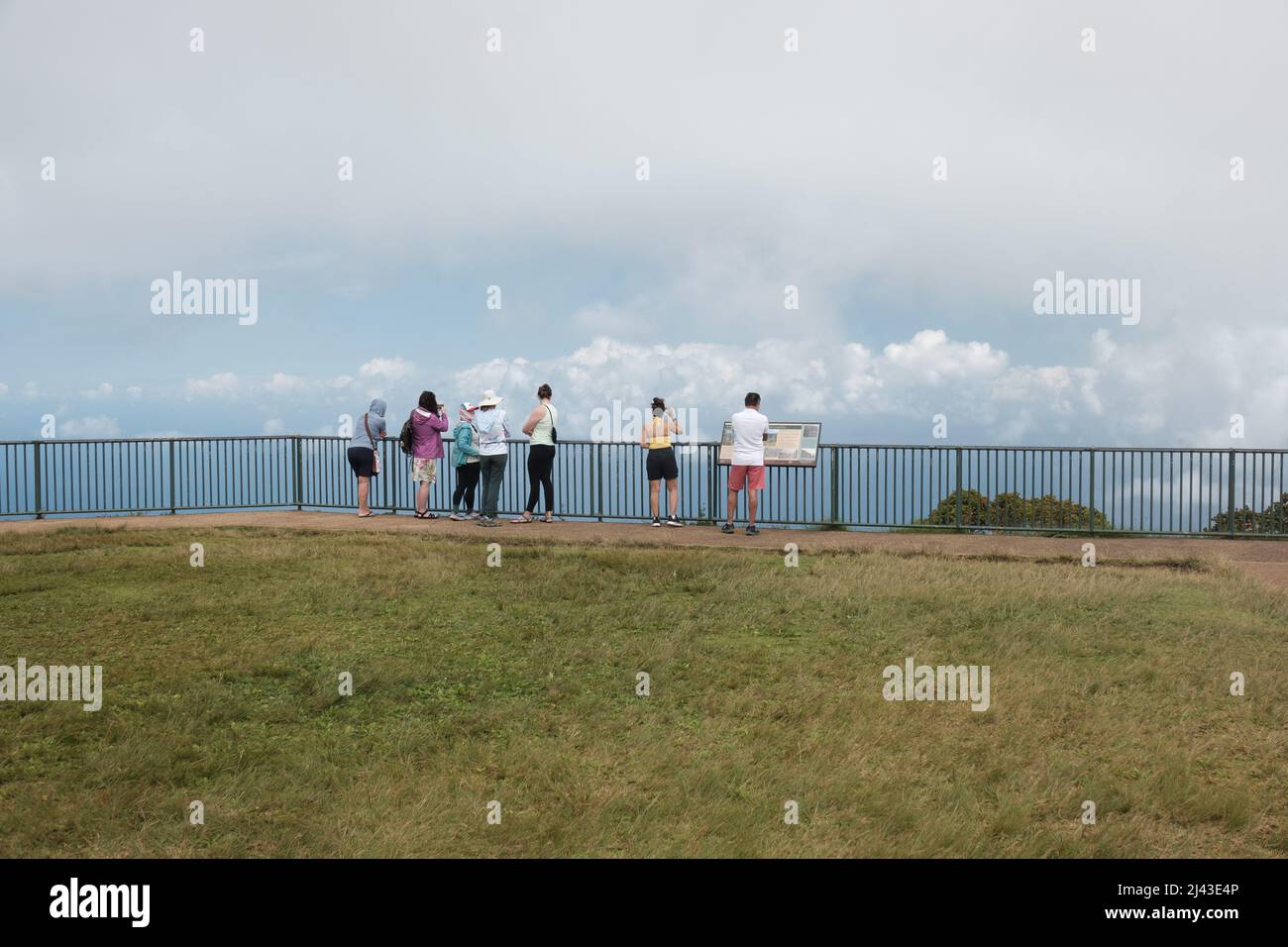 Touristen sehen Wolken über Zaun Stockfoto