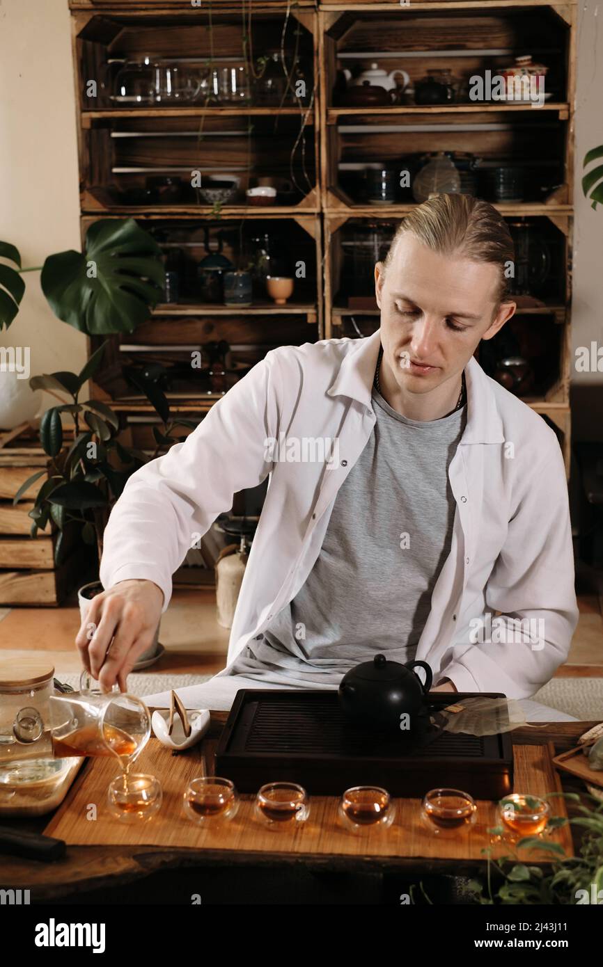 Schöne traditionelle chinesische Zeremonie Gun Fu Cha. Meister gießt Oolong aus einer Teekane mit Dampf auf einem dunklen Hintergrund Stockfoto