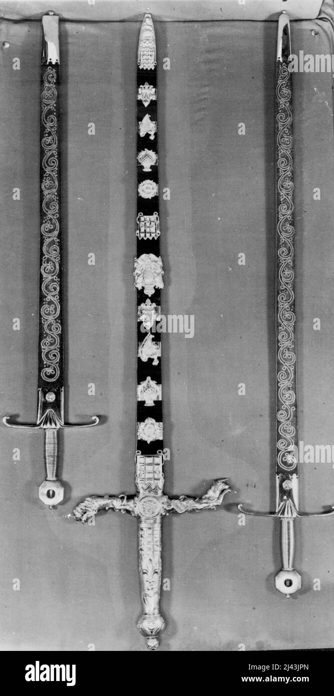 Die Kronjuwelen. Die Drei Staatsschwerter. Das Schwert des Staates (in der Mitte) ist ein zweihändiges Schwert, dessen Länge 32 Zoll beträgt. Der Griff ist aus vergoldetem Metall, die Kreuzstücke repräsentieren den Löwen und das Einhorn. Die Scheide ist mit Diamanten, Rubinen und Smaragden in Designs der Rose, des Thistles und des Schamrocks verziert. Bei der Krönung der Peer, der den Kämmerer trägt, der im Gegenzug das Juwelenschwert übergibt. Das Schwert auf der linken Seite ist das Schwert der Gerechtigkeit für die Spiritualität, während das dritte Schwert das Schwert der Gerechtigkeit für die Zeitlichkeit ist. 01. September 1952. (Foto von Stockfoto