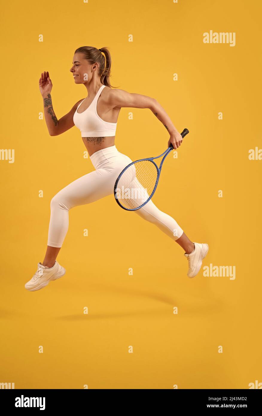 Glücklicher Tennisspieler läuft mit Schläger auf gelbem Hintergrund, Badminton Stockfoto