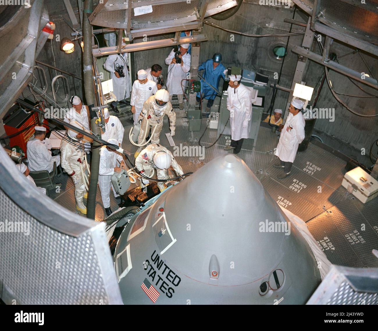 Die Apollo 1-Besatzungsmitglieder der ersten bemannten Apollo-Mission bereiten sich darauf vor, ihre Raumsonde in die Höhenkammer des Kennedy Space Center (KSC) zu betreten. Beim Betreten der Luke ist Astronaut Virgil (Gus) Grissom, Kommandopilot; hinter ihm ist Astronaut Roger Chaffee, Pilot; links mit Kammertechnikern steht Astronaut Edward White, leitender Pilot. Sie wurden alle einige Monate später bei dem Brand getötet. Stockfoto