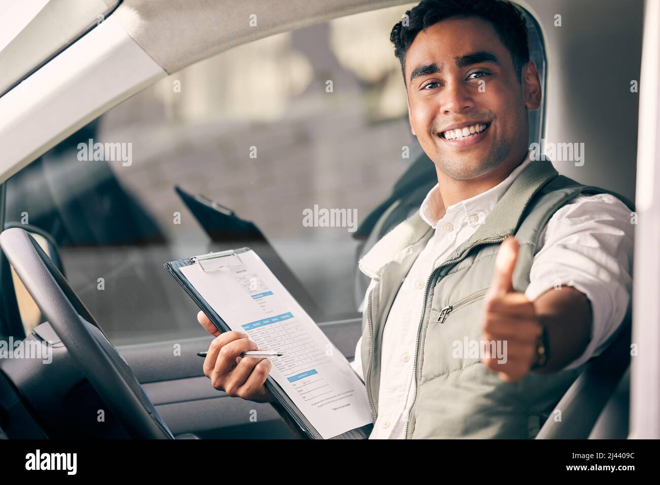 Ihr Paket ist in den besten Händen. Aufnahme eines Lieferers, der ein Klemmbrett hält und den Daumen hoch zeigt, während er in seinem Fahrzeug sitzt. Stockfoto