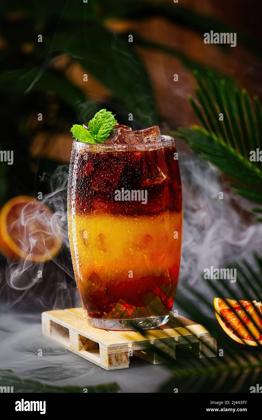 Bumble Kaffee mit Eis auf einem dunklen tropischen Hintergrund. Espresso, Orangensaft und Sirup in Schichten Stockfoto