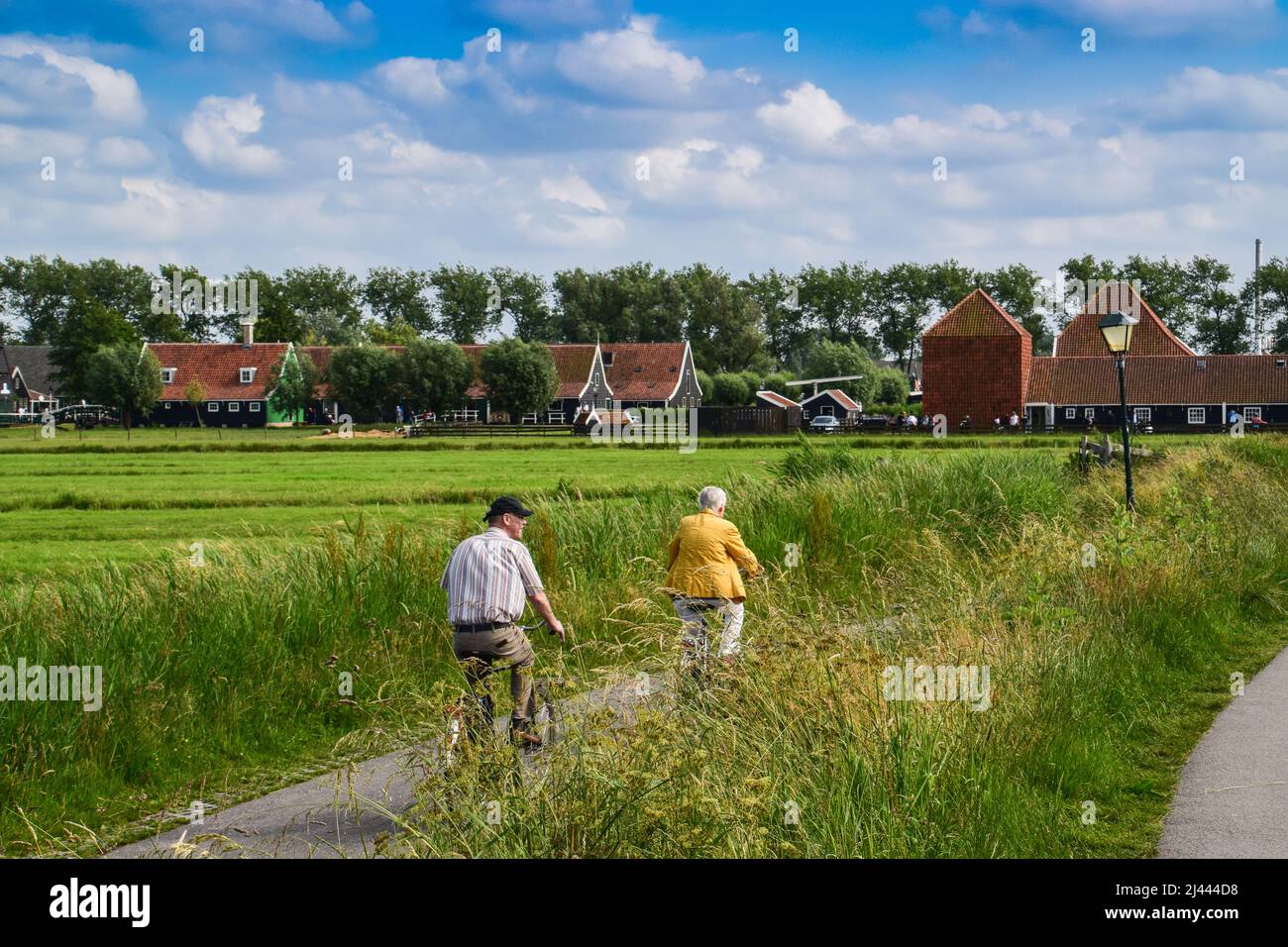 Ältere Menschen auf einem Fahrrad auf einer Landstraße in Zaanse Schans, Niederlande Stockfoto
