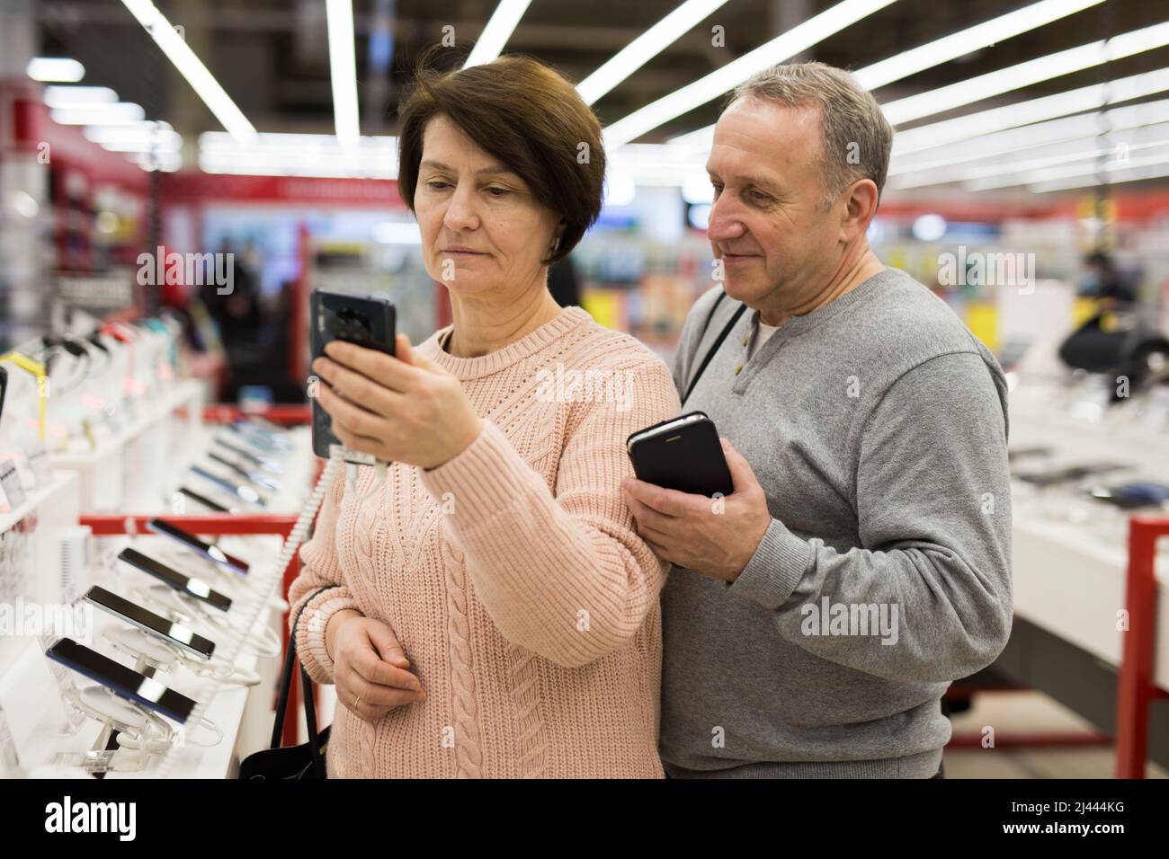 Seniorenpaar, das sich im Technikgeschäft für ein Smartphone entschieden hat Stockfoto