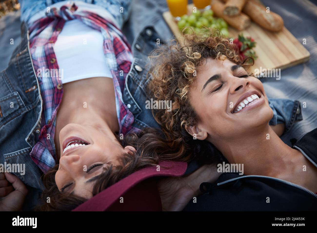 Ihr bringt mich zum Lachen. Kurzer Schuss von zwei jungen Frauen, die auf einer Picknickdecke liegen. Stockfoto
