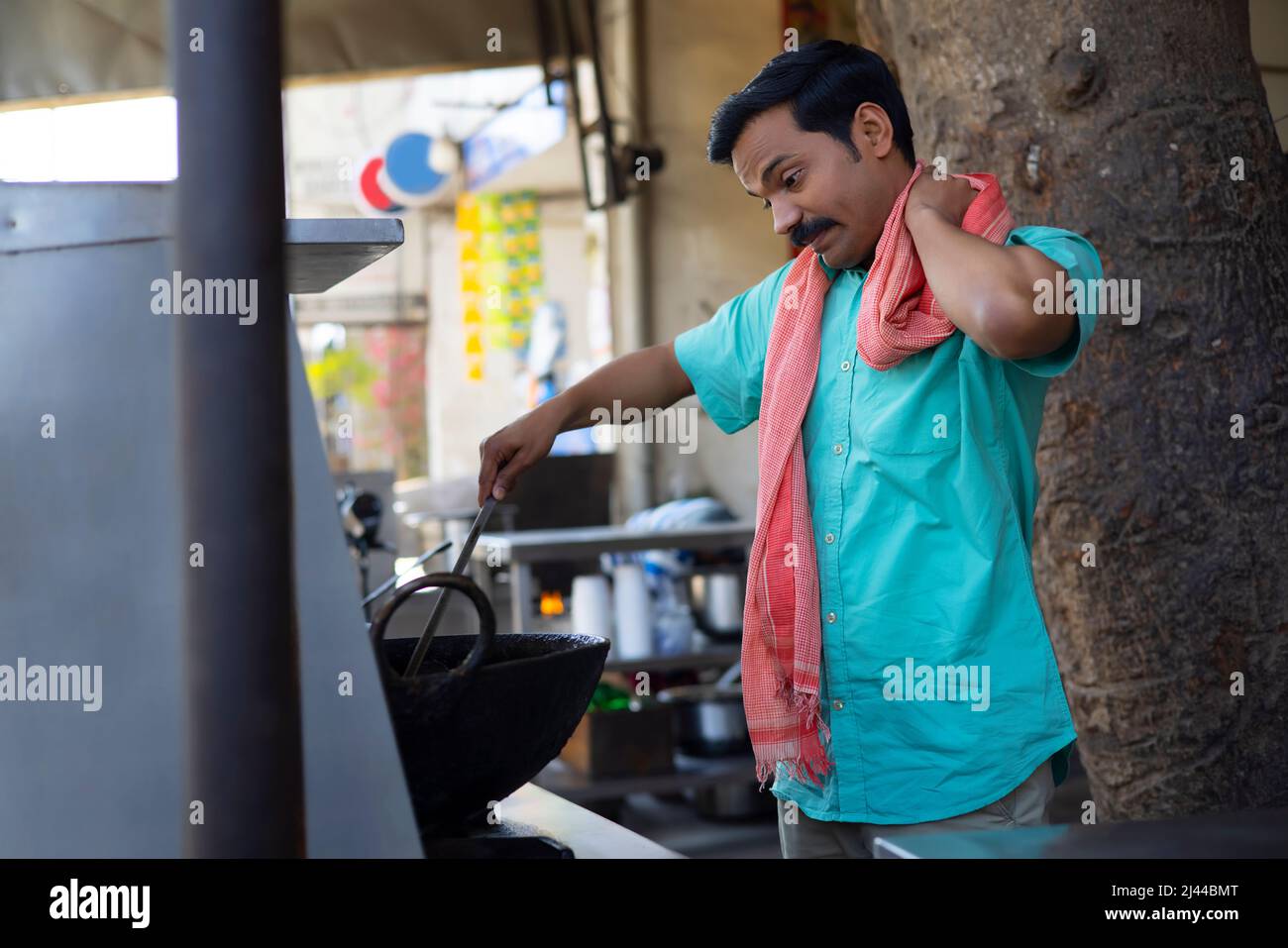 Porträt eines Straßenverkäufers, der an einem Stall Lebensmittel macht Stockfoto