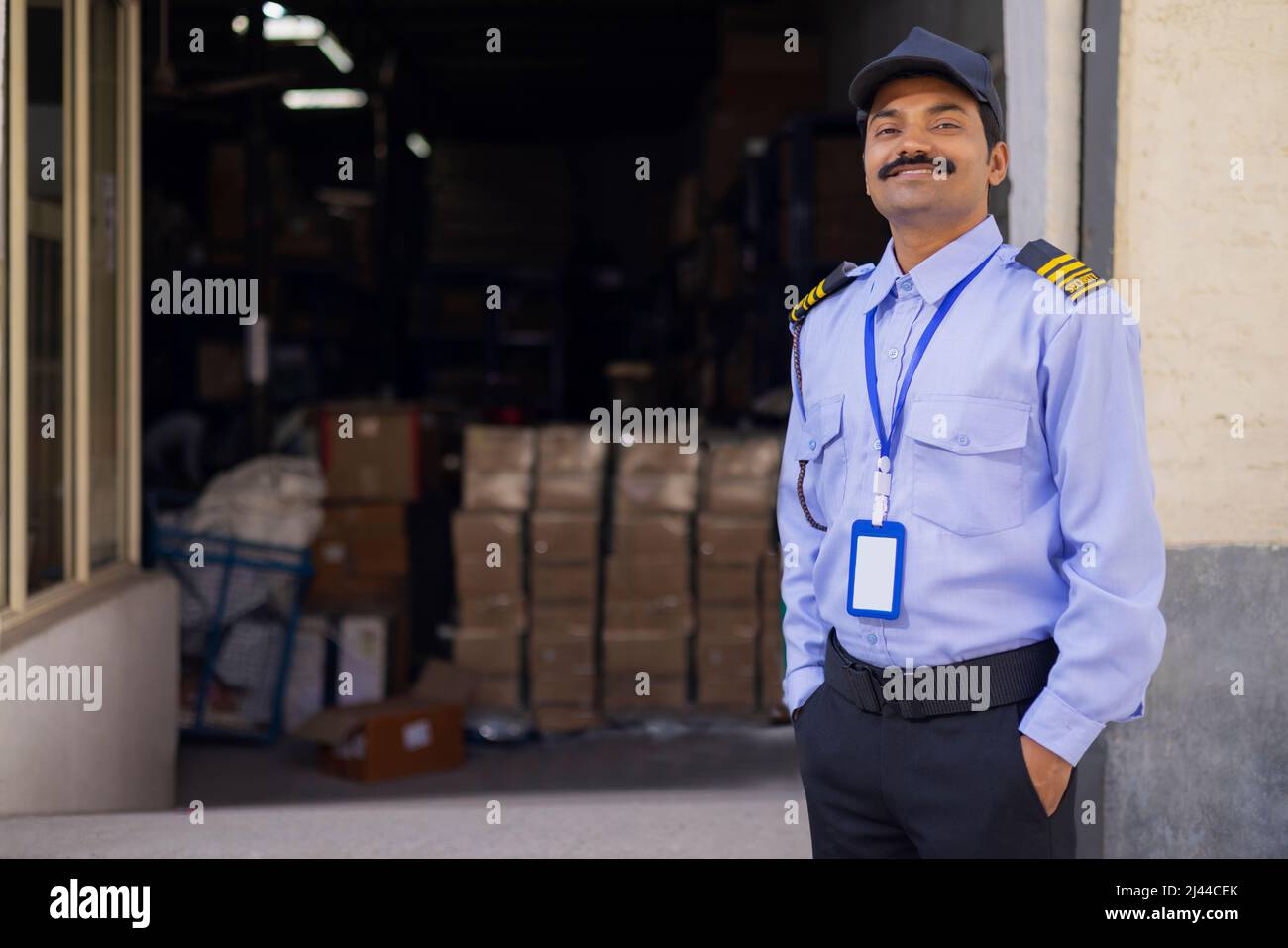 Porträt eines männlichen Sicherheitsbeamten mit Händen in den Taschen während der Arbeit im Lager Stockfoto