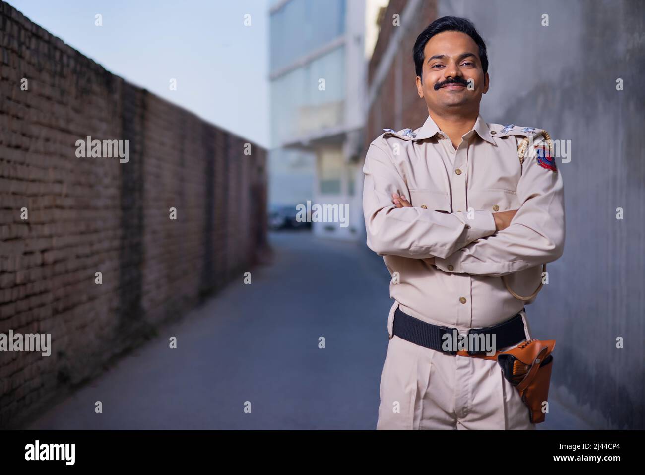 Porträt eines indischen Polizisten, der mit gefalteten Armen steht Stockfoto