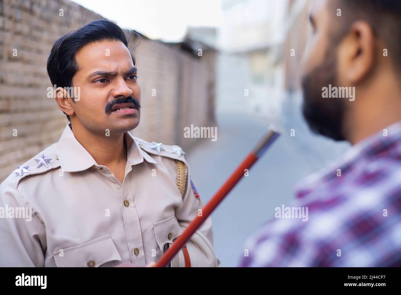 Indischer Polizist bedroht jemanden durch Anheben von Schlagstöcken Stockfoto
