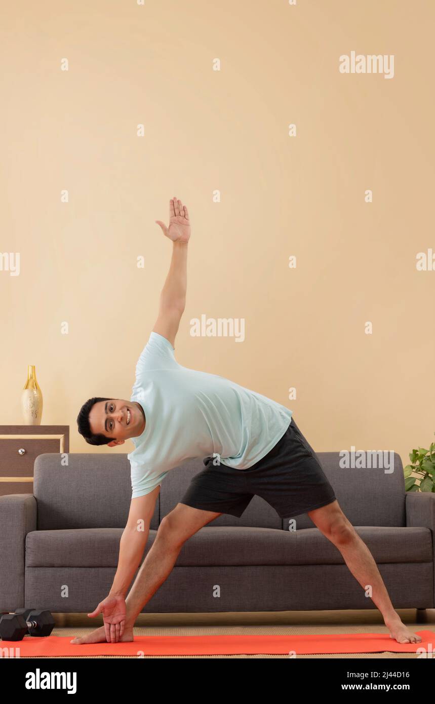 Porträt eines jungen Mannes, der zu Hause auf einer Trainingsmatte Yoga macht Stockfoto