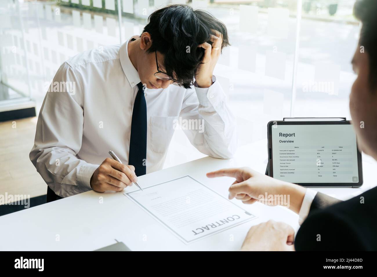 Der männliche Vorgesetzte spricht oder erklärt, dass er den Mitarbeiter entlassen muss, während ihm ein Rücktrittsschreiben ausgehändigt wird. Stockfoto