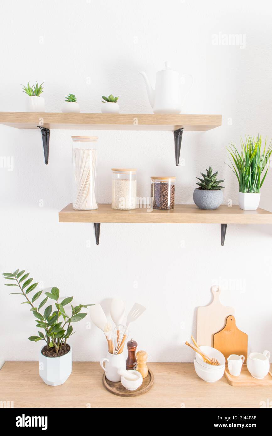 Vorderansicht der modernen Küche offene Regale mit Gläsern für die Lagerung von Lebensmitteln und Topfpflanzen. Teil der Arbeitsplatte mit Küchenutensilien Stockfoto
