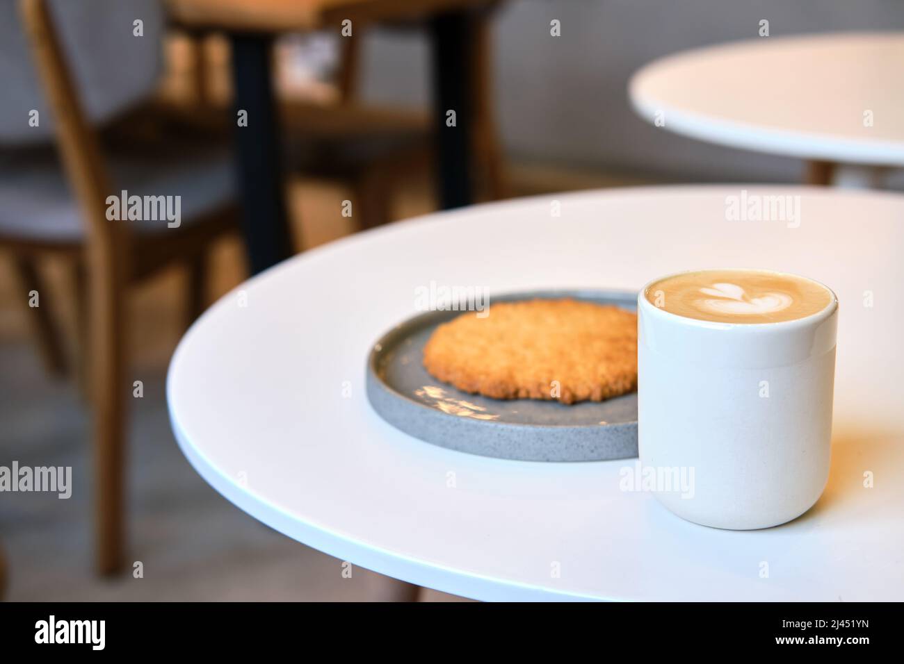 Der morgendliche Brunch im Café ist auf dem Tisch. Riesenkeks und Cappuccino mit schönem Milchschaum. Manchmal muss man in dieser schnelllebigen Welt eine Pause einlegen Stockfoto