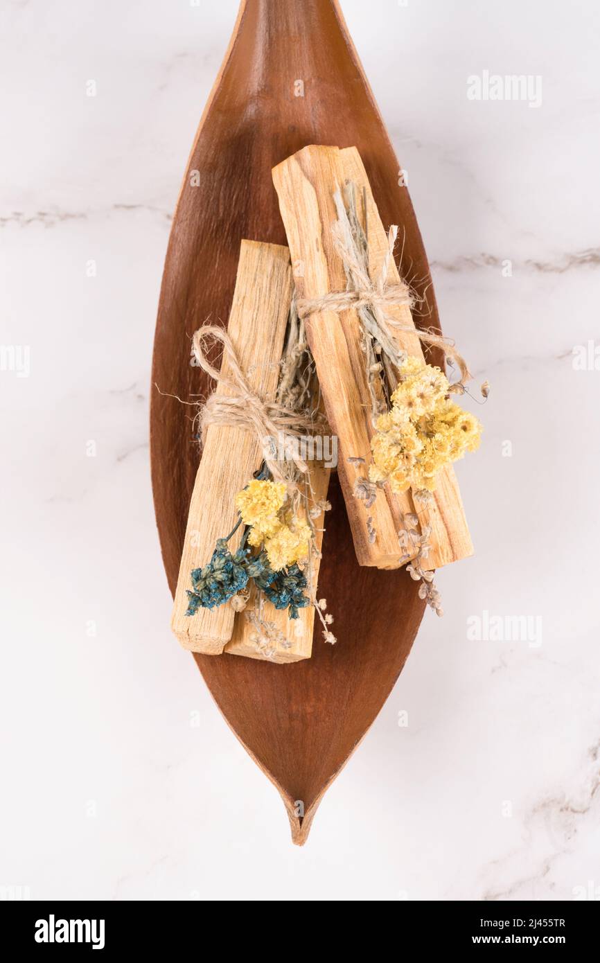 Vertikales Bild von palo santo Sticks mit Blumensträußen aus getrockneten Blumen auf weißem Marmortisch Hintergrund. Flache Lay-Komposition mit heiligen Holzstäben für mich Stockfoto