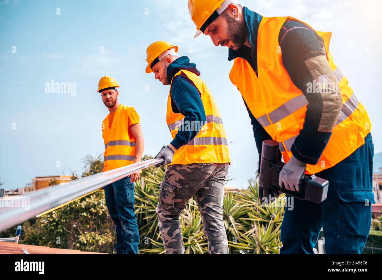 Ein Team von Technikern arbeitet auf dem Dach eines Hauses Stockfoto