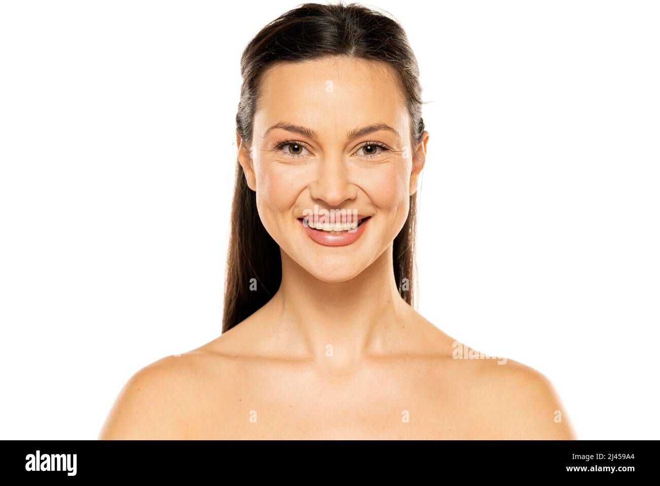 Eine junge glückliche Frau ohne Make-up mit langen Haaren auf weißem Hintergrund. Stockfoto