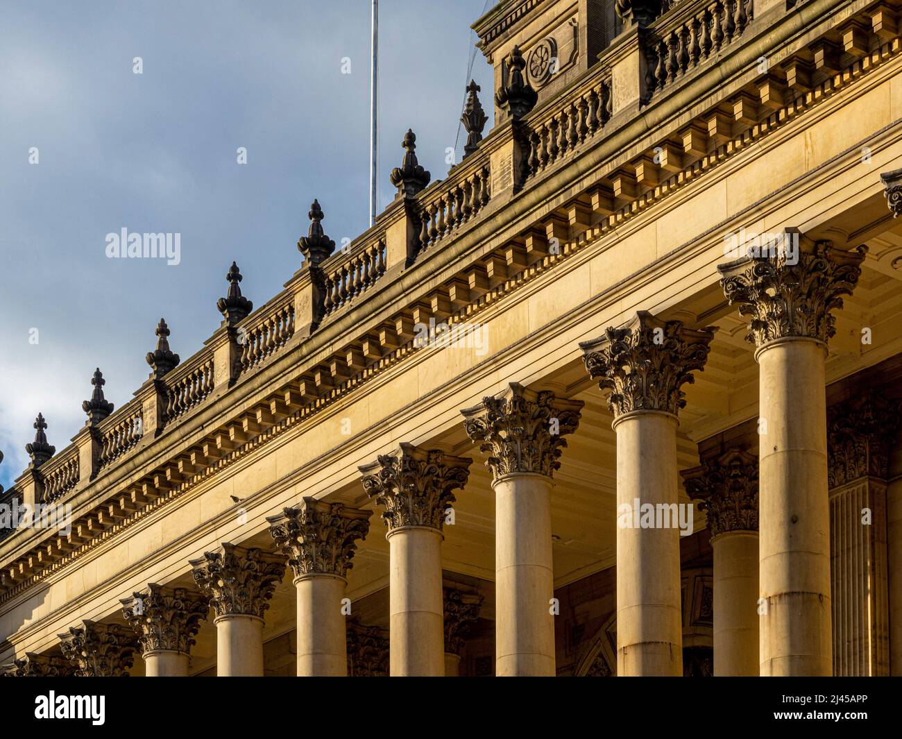 Nahaufnahme der kunstvoll geschnitzten Steinhauptstädte und des Gesims des Rathauses von Leeds, gesehen von einem blauen Himmel. Leeds, West Yorkshire, Großbritannien Stockfoto