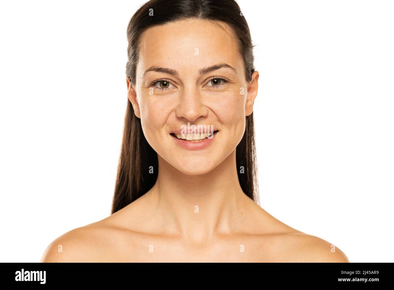 Eine junge glückliche Frau ohne Make-up mit langen Haaren auf weißem Hintergrund. Stockfoto