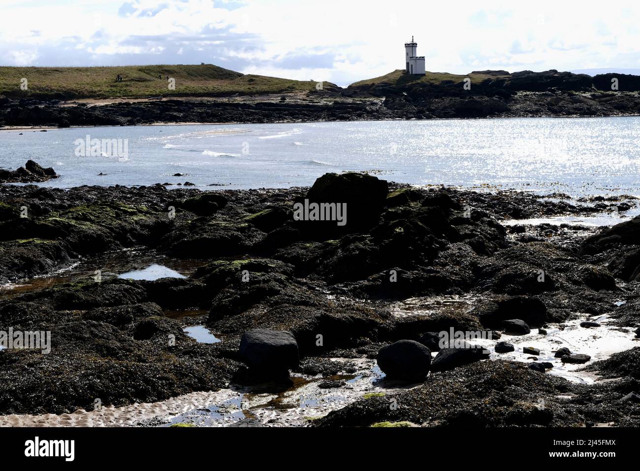 Elie Fife Schottland ein Küstenresortdorf, die Flut ist draußen und Einheimische und Touristen genießen einen Spaziergang am Strand. Blauer Himmel an einem frühen Frühlingstag. Stockfoto