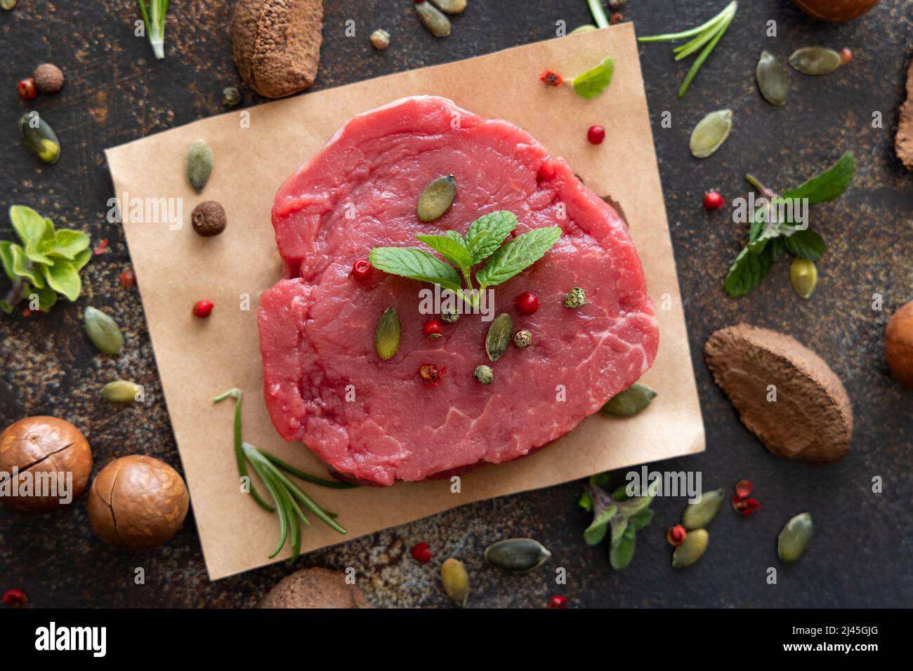 Roh-Rinderfilet-Steaks auf dunklem Tisch. Portioniertes Filet Mignon mit Gewürzen und Kräutern. Konzept der Sommerkost. Stockfoto