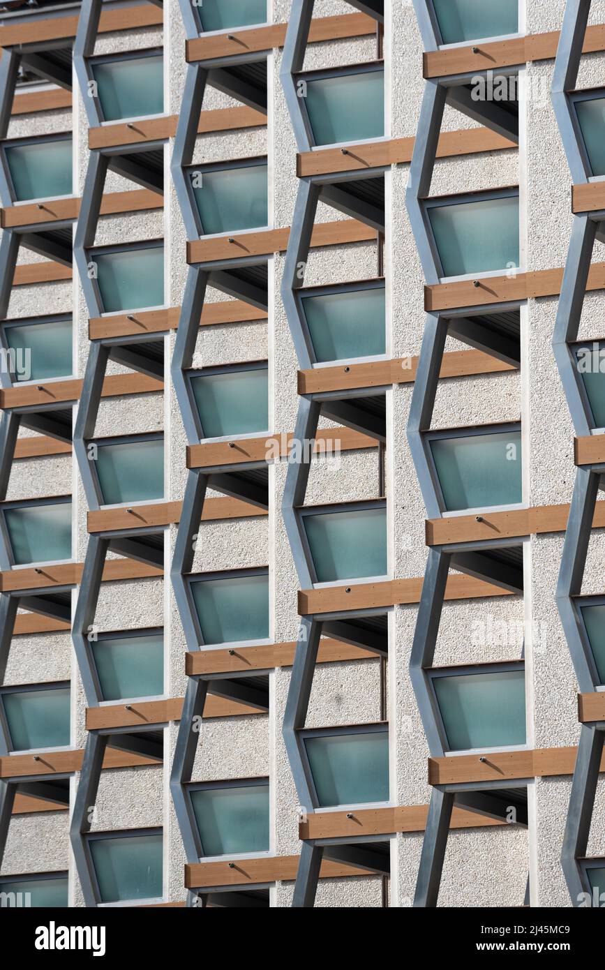 Architektonische Nahaufnahme der Gebäudefassade aus Schindelbeschichtung mit Fenstern und Balkonen, die von Metallträgern in symmetrischen Mustern in Chamonix unterstützt werden Stockfoto