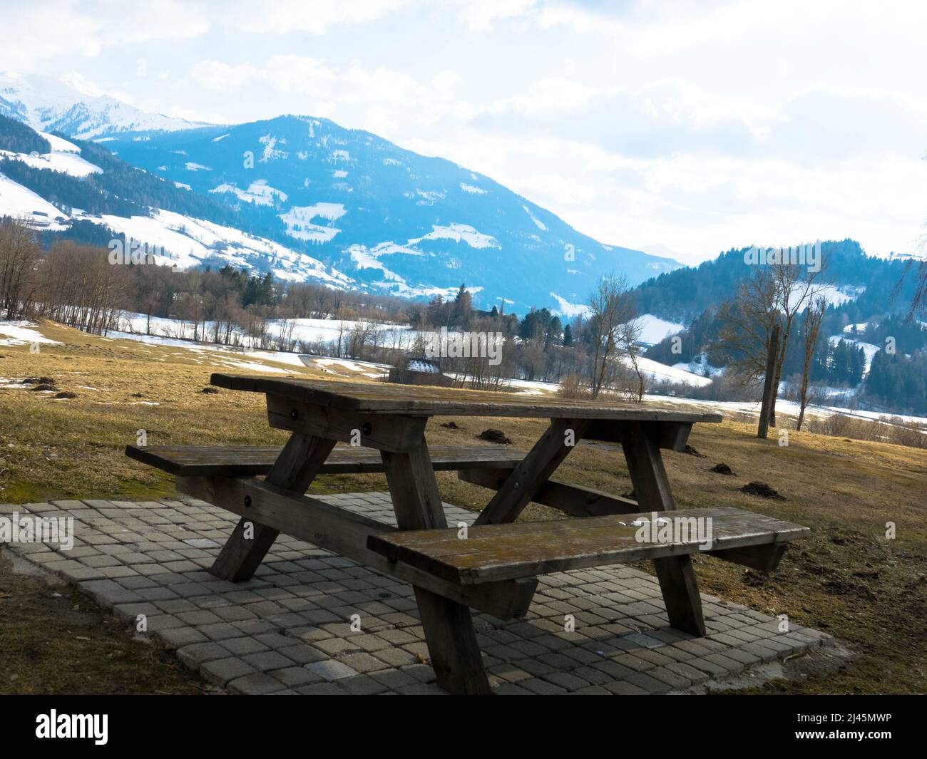 Holzpicknicktisch mit Bänken im Rastplatz abseits der Autobahn mit Bergen im Hintergrund. Salzburg, Oberösterreich. Stockfoto