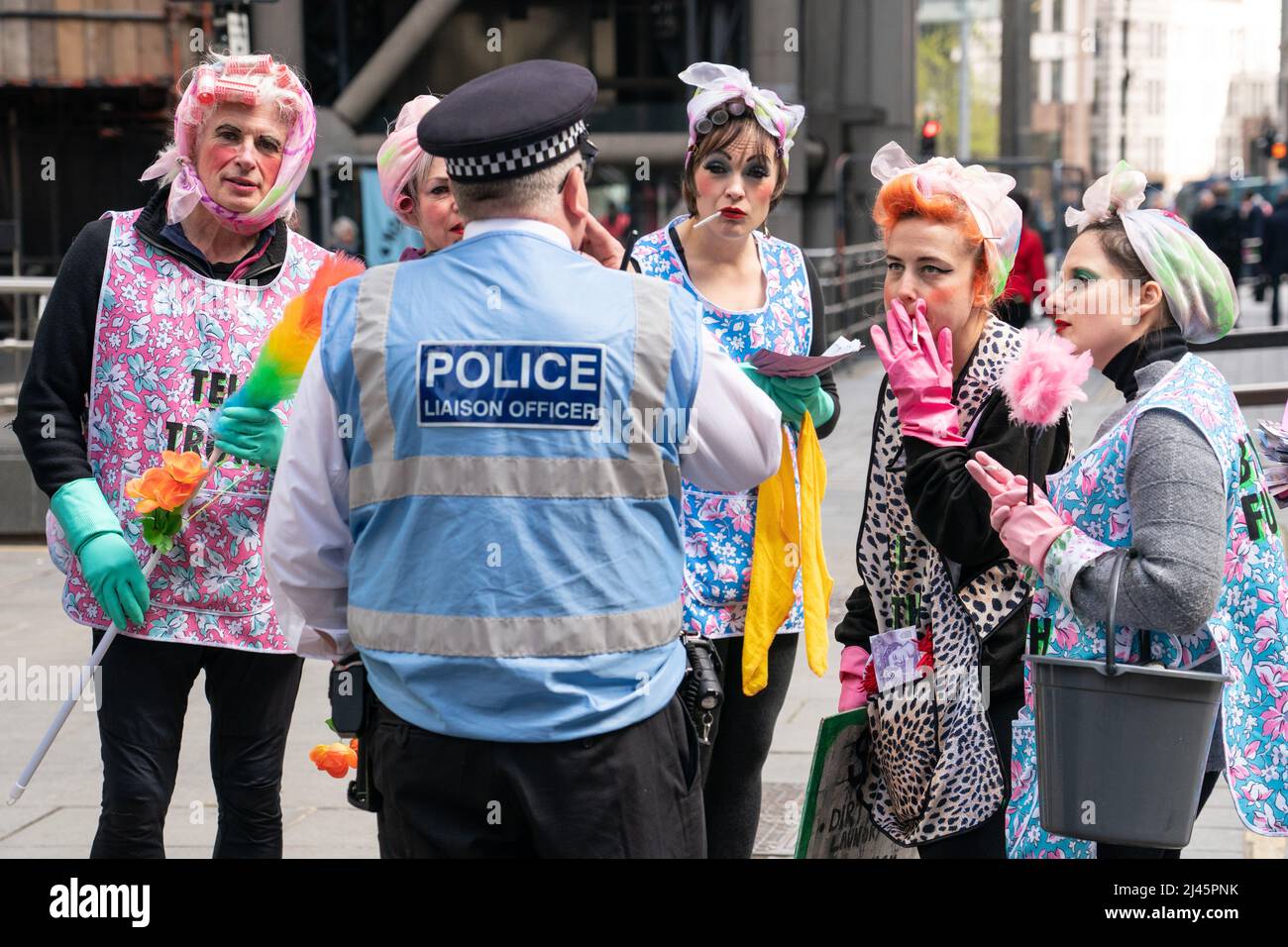 Aktivisten des Extinction Rebellion sprechen in Putzfrauen-Kleidung mit einem Polizeibeamten außerhalb von Lloyds of London in der City of London, während sie Lloyds dazu aufrufen, die Versicherung von Projekten für fossile Brennstoffe weltweit einzustellen. Bilddatum: Dienstag, 12. April 2022. Stockfoto