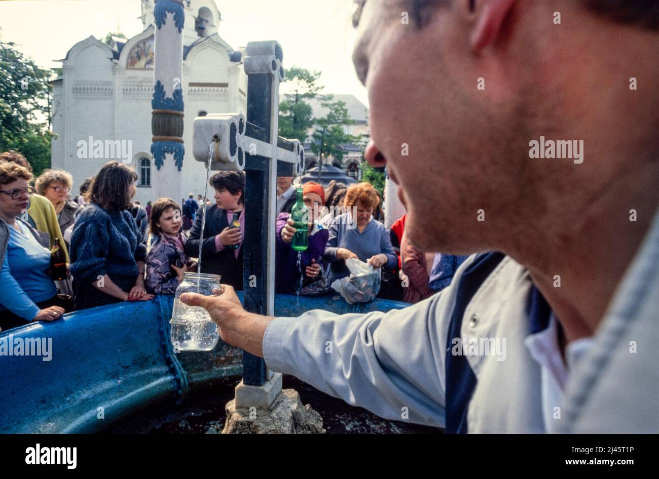 Menschen sammeln Wasser aus einer heiligen Quelle auf dem Gelände des Dreifaltigkeitslawra des heiligen Sergius, dem wichtigsten russischen Kloster der russisch-orthodoxen Kirche, in Sergijew Posad, 70 km von Moskau entfernt. Mai 1990 Stockfoto